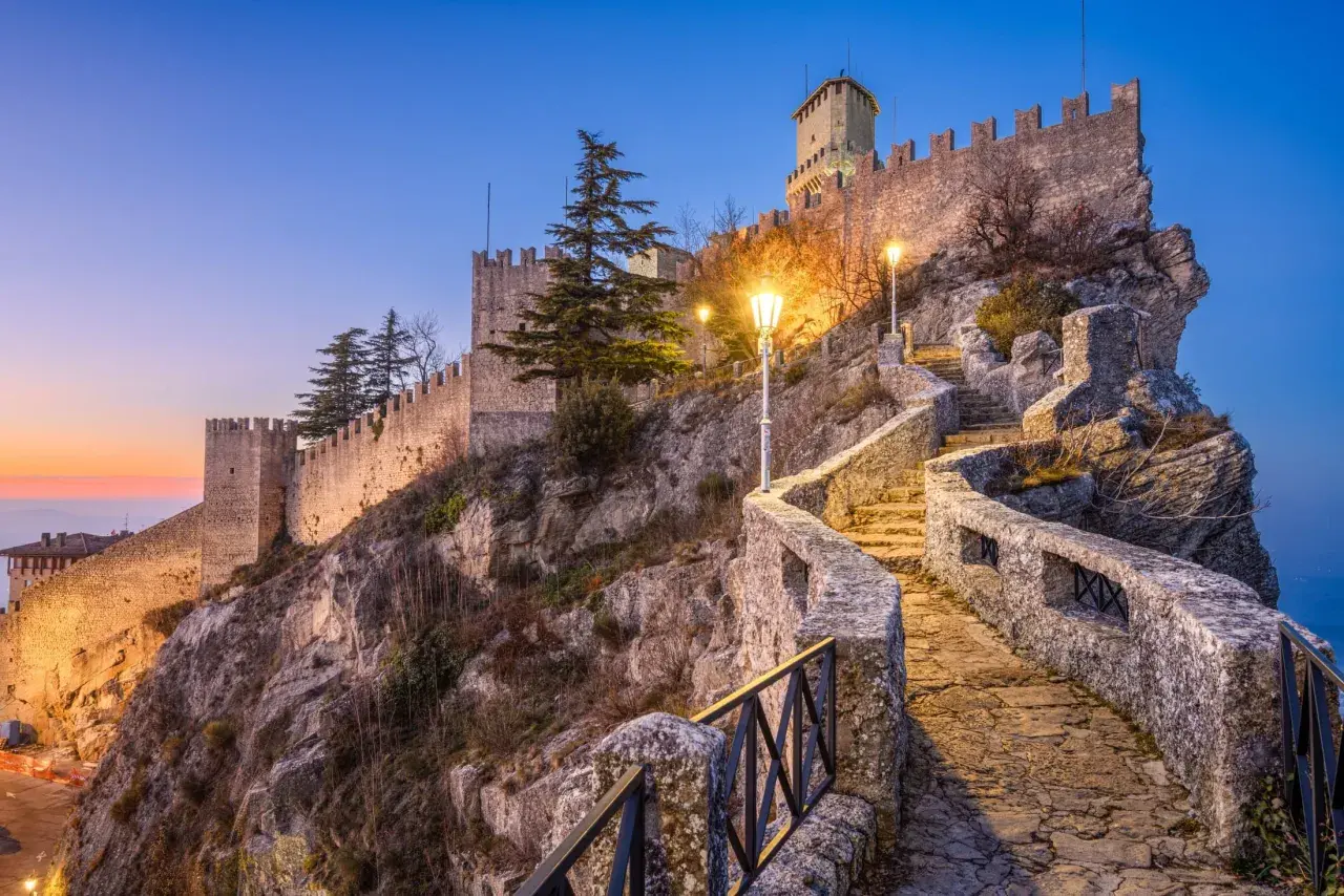Kamienne schody prowadzą do twierdzy w San Marino, oświetlone latarniami.