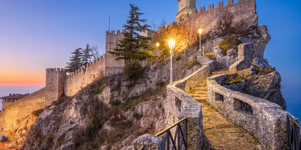 Kamienne schody prowadzą do twierdzy w San Marino, oświetlone latarniami.