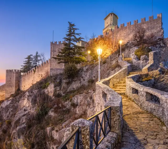 Kamienne schody prowadzą do twierdzy w San Marino, oświetlone latarniami.