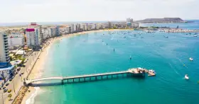 Malecón w Manta, Ekwador. Widok na plażę, budynki, molo i zatokę z łodziami. Tu właśnie leży Ekwador, kraj na równiku.
