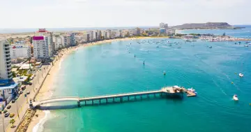 Malecón w Manta, Ekwador. Widok na plażę, budynki, molo i zatokę z łodziami. Tu właśnie leży Ekwador, kraj na równiku.